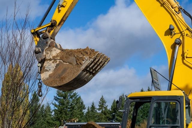 A yellow excavator lifts dirt from the ground showcasing its powerful machinery in action