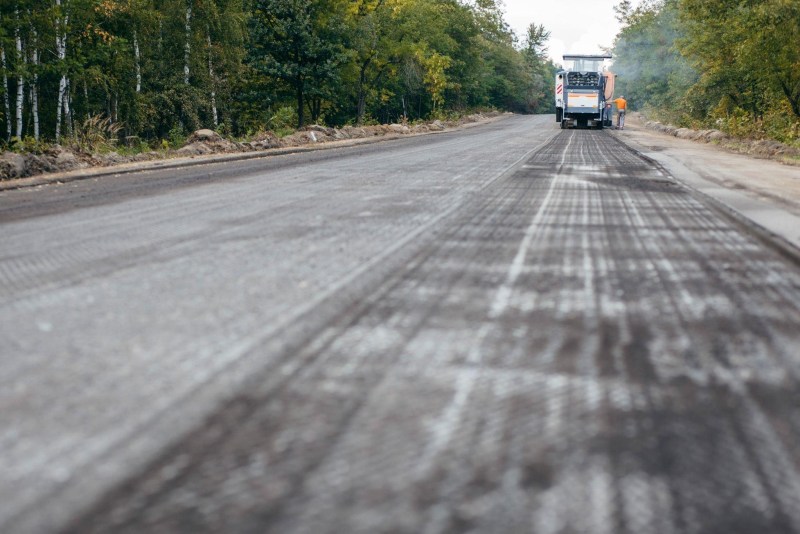A truck driving along a smooth asphalt road surrounded by greenery