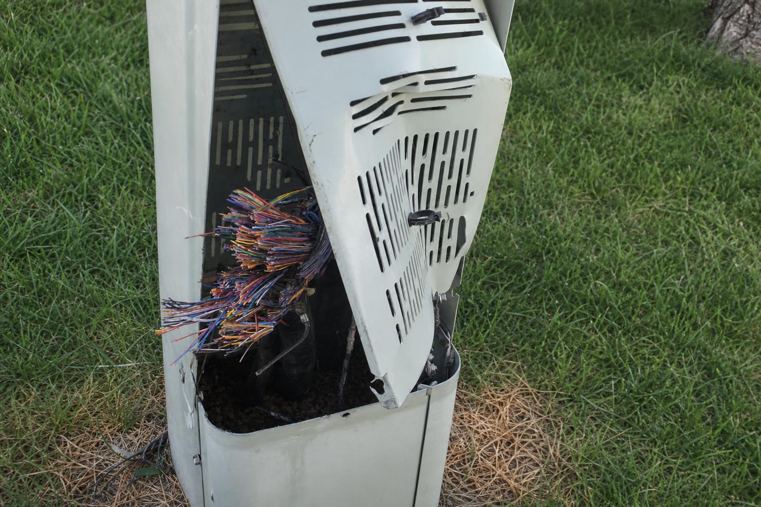 Damaged telecommunications pedestal near a Colorado roadway after copper wire theft