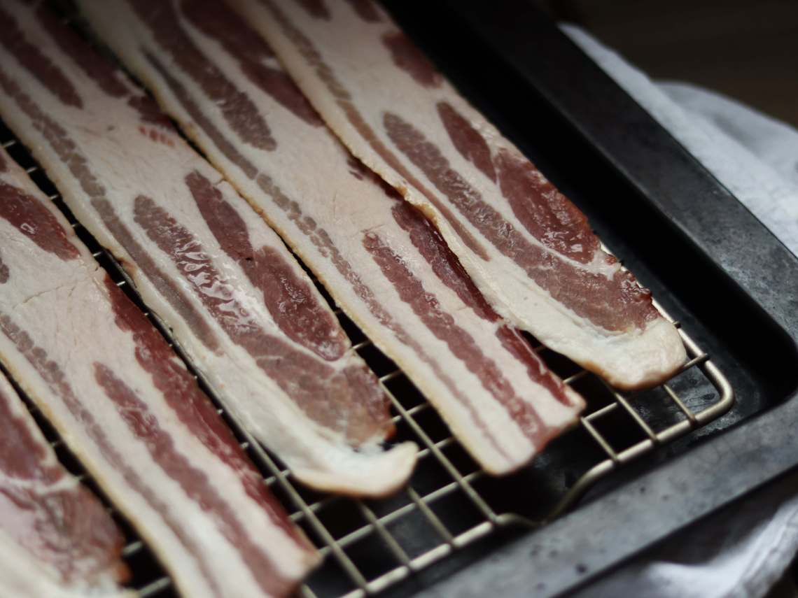 uncooked bacon on a baking sheet