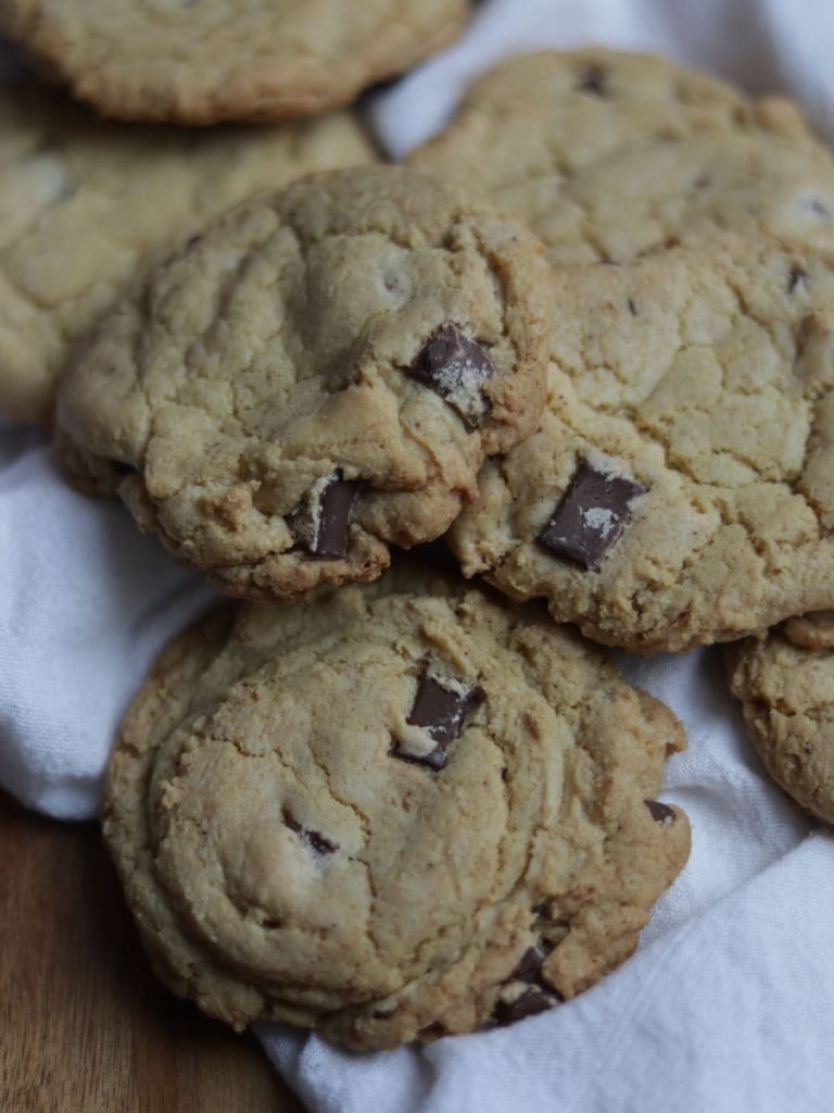 sourdough discard brown butter chocolate chip cookies on a wooden cutting board and linen cloth