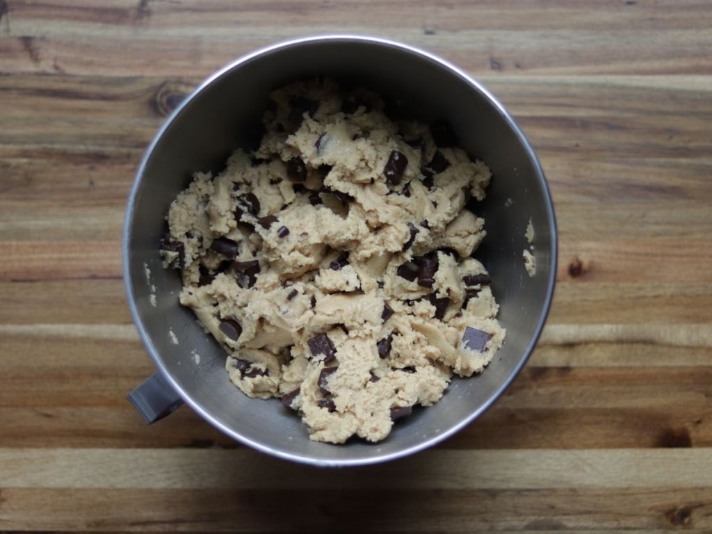 overhead image of sourdough discard brown butter chocolate chip cookie dough in a mixing bowl on a wooden cutting board