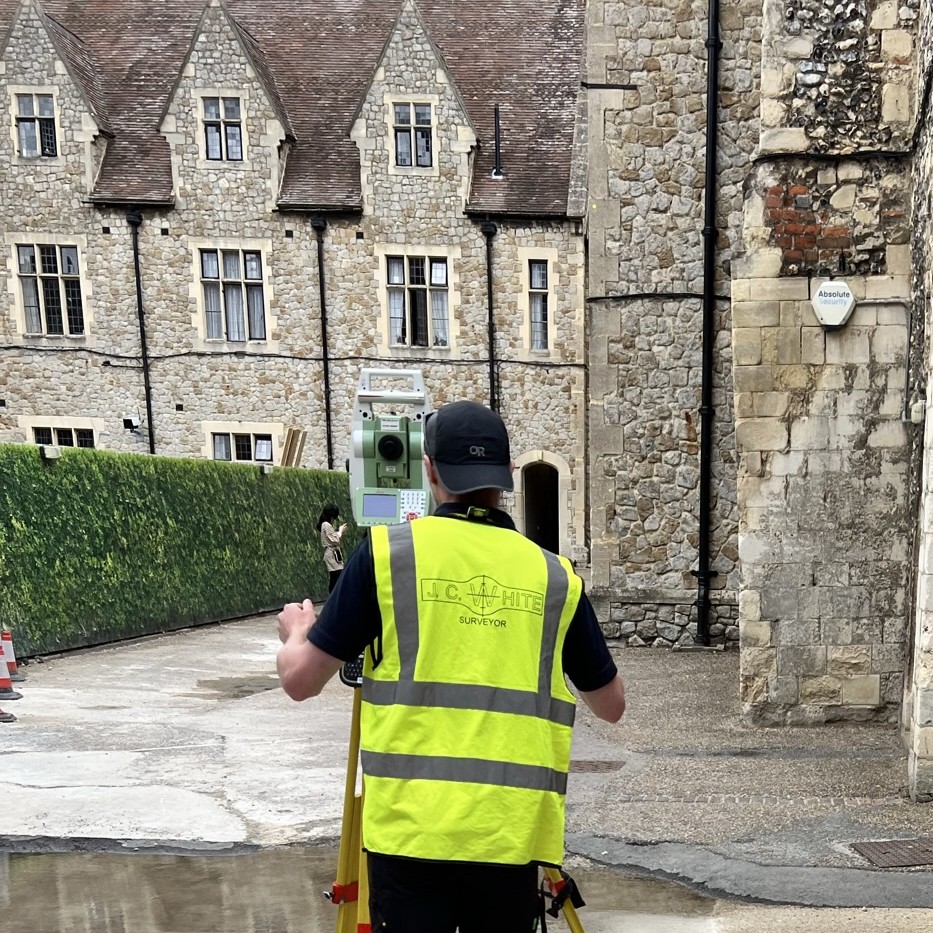 land surveyor with total station in front of an old stone building