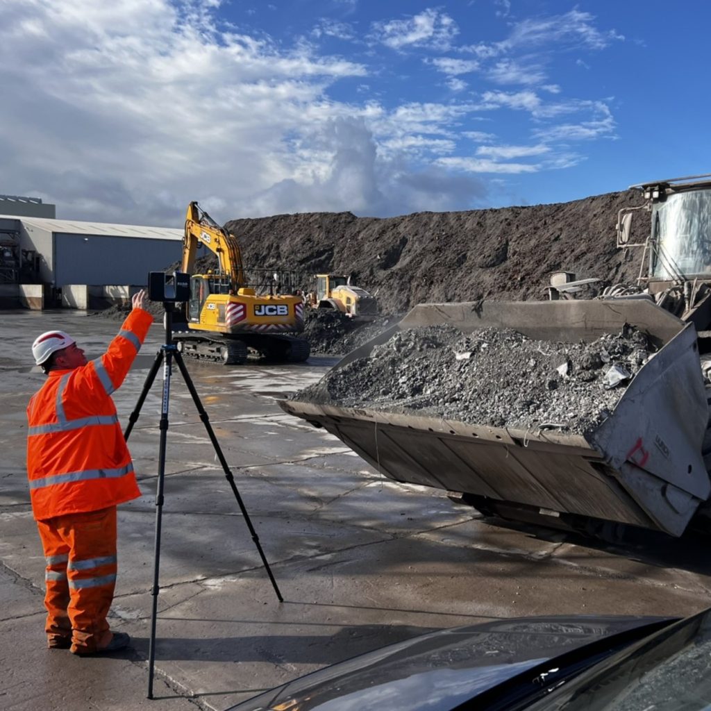 surveyor with a 3d laser scanner collecting volume information in an aggregate yard