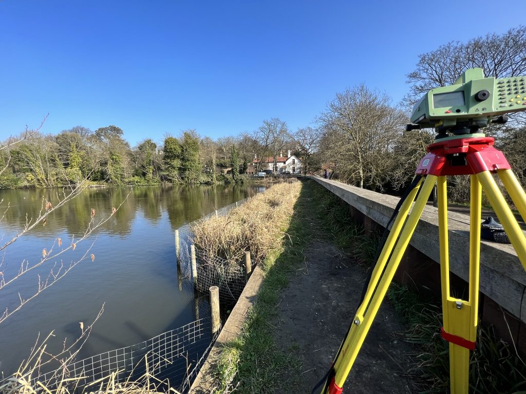 digital level on tripod on retaining structure of reservoir