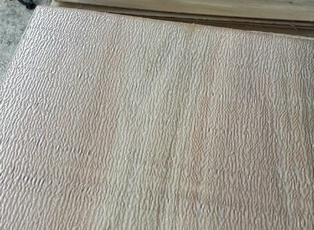 The adhesive is applied evenly across the plywood veneer.