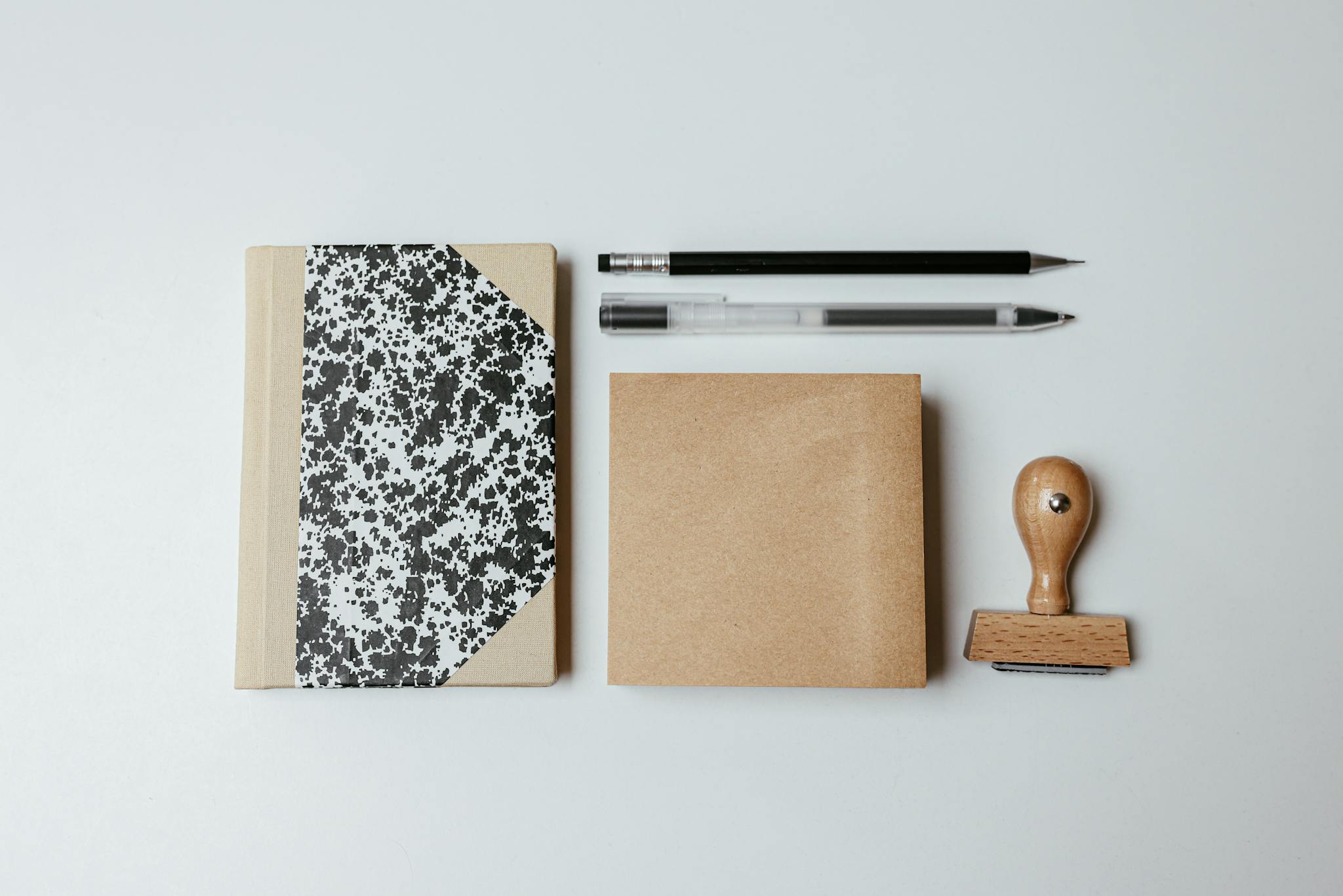 A modern flatlay featuring a notepad, pens, and a wooden stamp on a clean background.