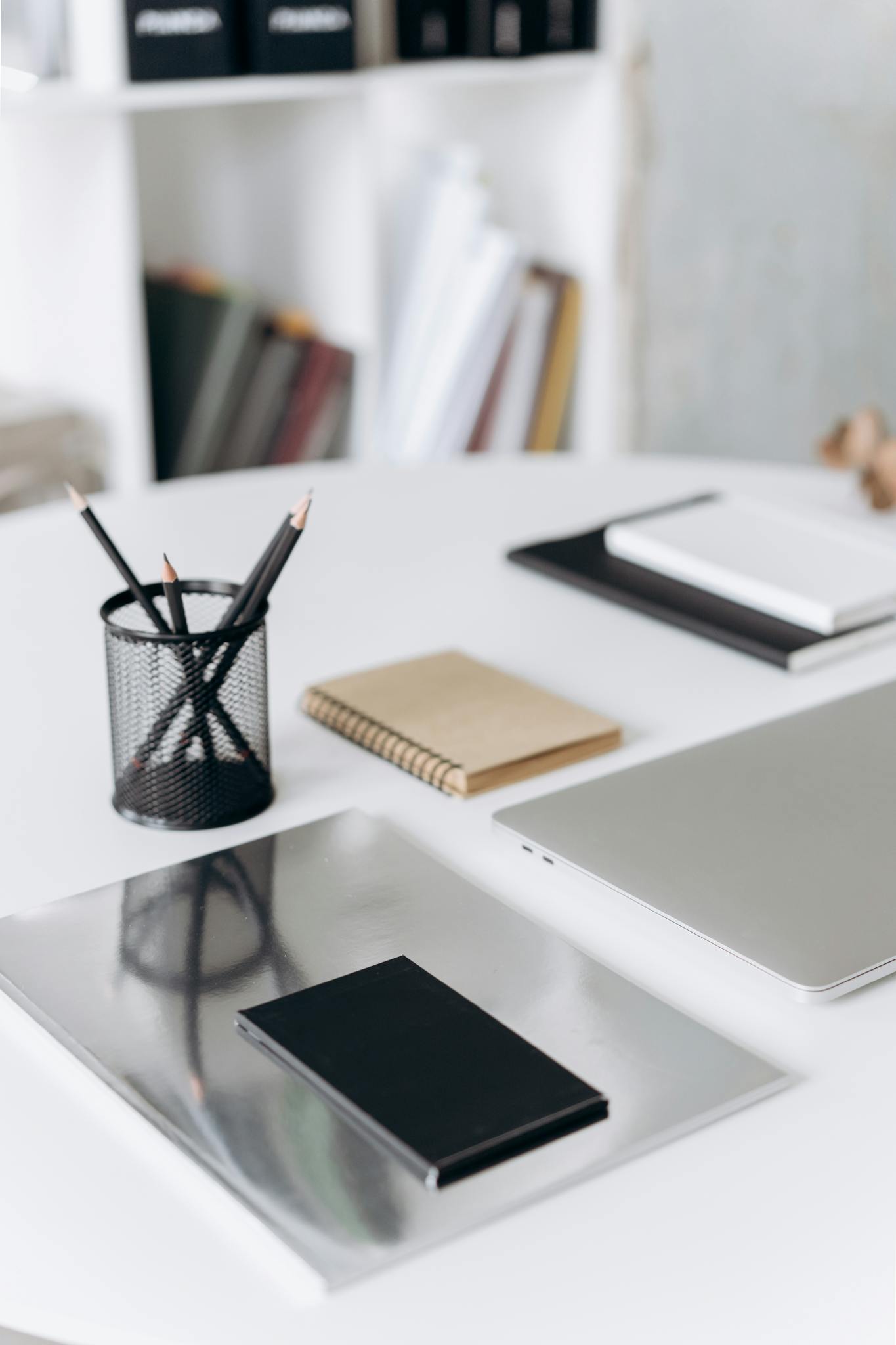 A neat and organized office desk setup with notebooks, pencils, and a laptop in a modern workspace.
