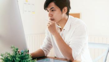 Ein Selbstständiger grübelt vor seinem PC über Webdesign.