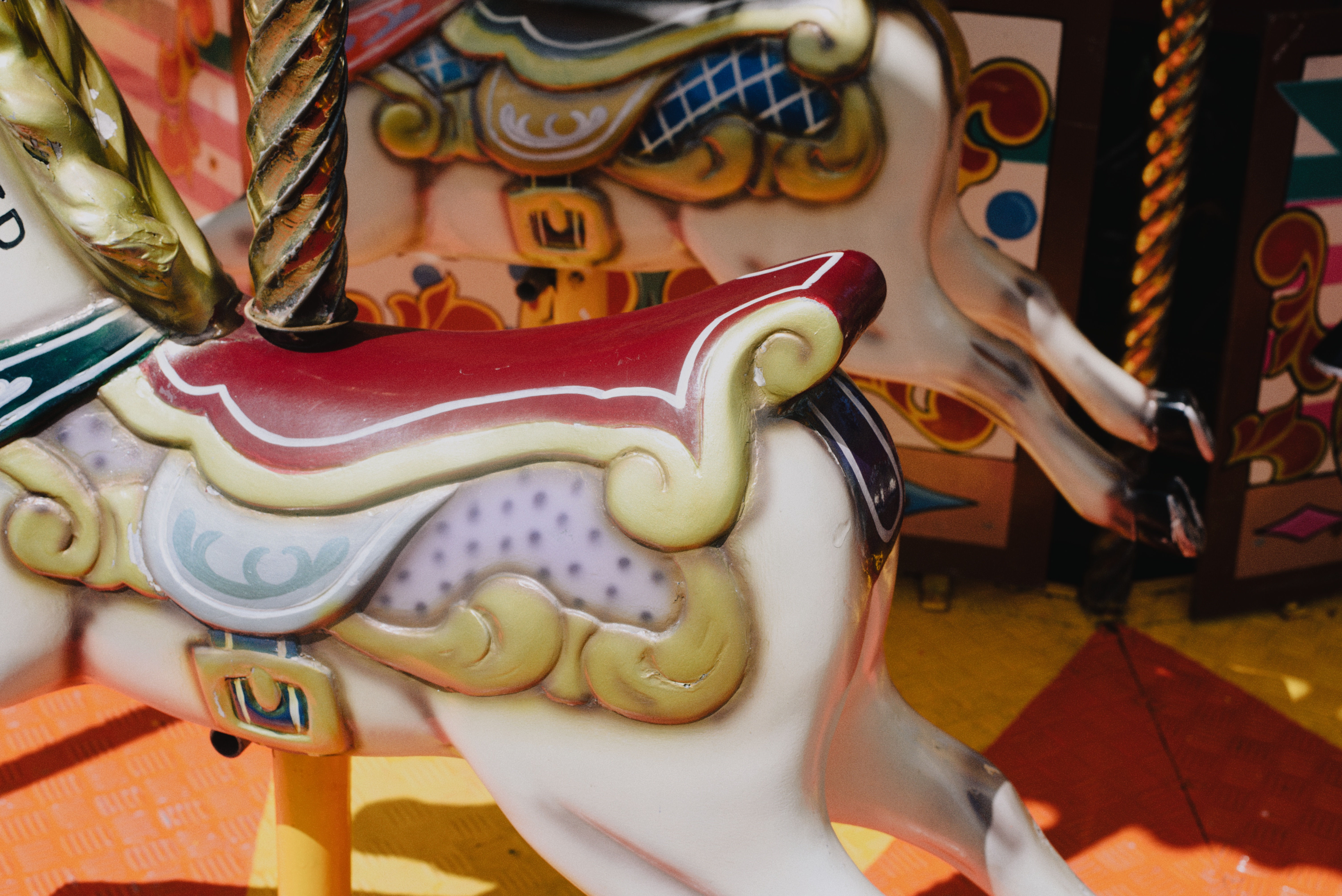 The horse — a carousel horse's head in close-up, red mane and gold scrollwork, a brass pole rising past its neck