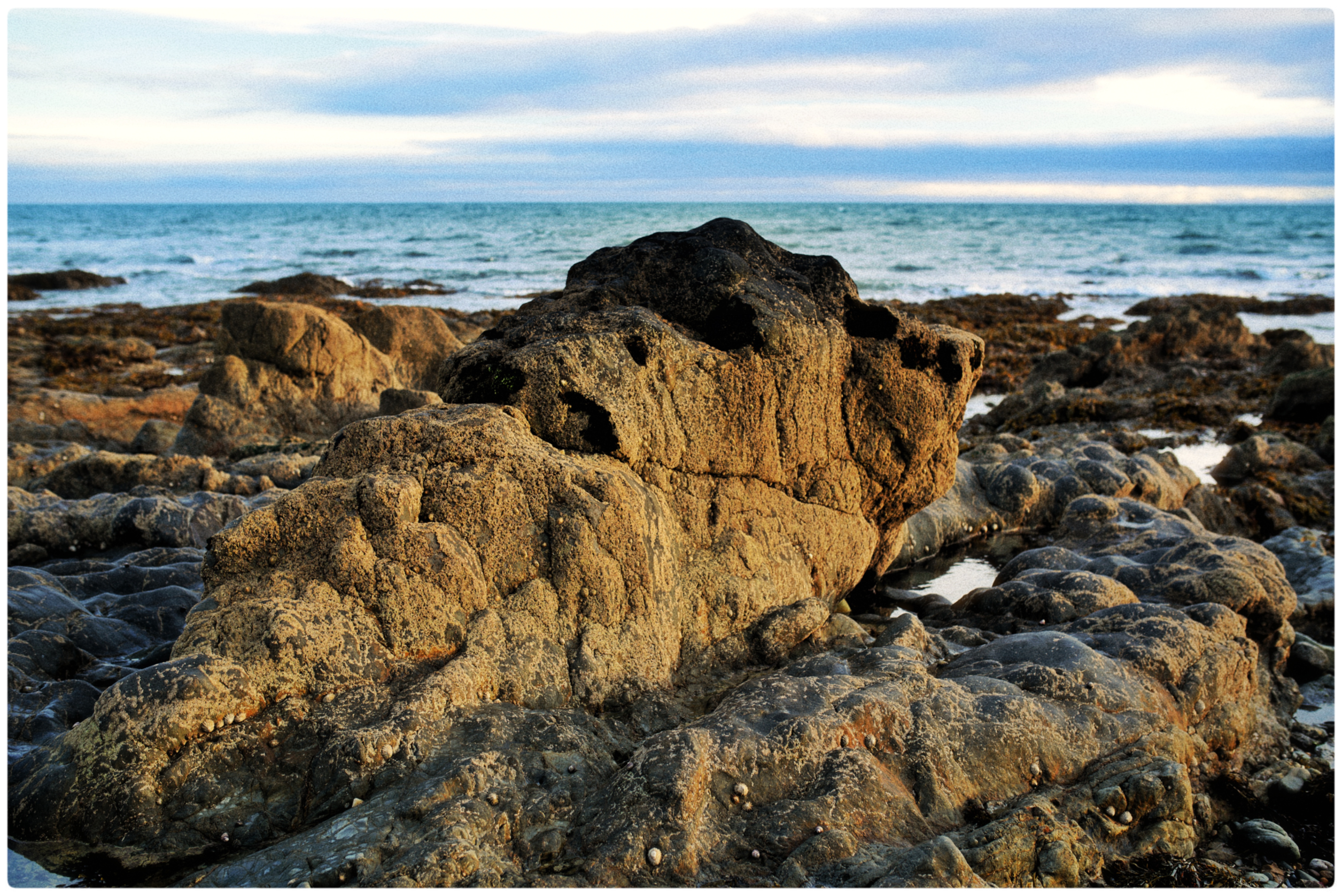 Wexford setting sun — low sun across a rocky shore, the sea and a banded sky beyond