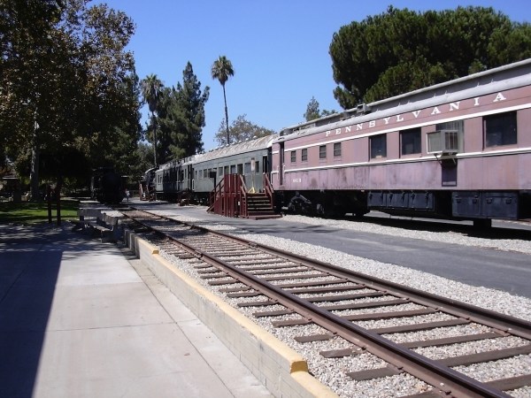 Auto-generated description: A vintage railway car labeled Pennsylvania is parked on train tracks, surrounded by trees.
