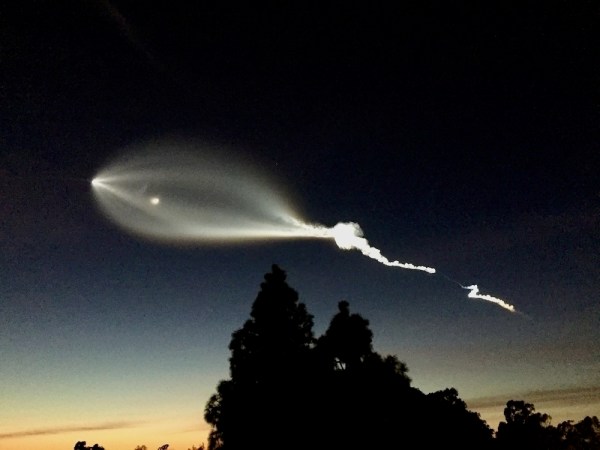 Auto-generated description: A glowing streak of light trails across the twilight sky, resembling a rocket launch or celestial event.