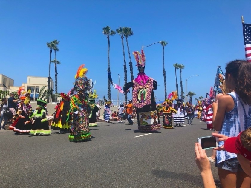 community.jpeg Cultural dancers in a parade as the crowd looks on.