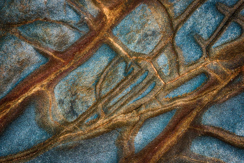 Geological rock striations and patterns in a mix of reds and blue along the California coast
