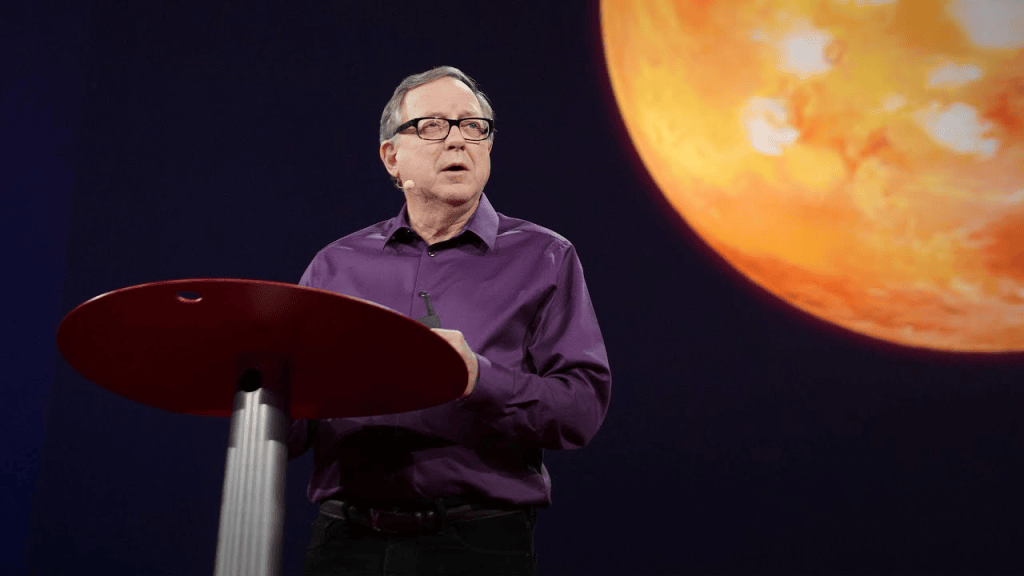 Stephen Petranek delivers a TED talk on the potential for human life on Mars, with a large image of Mars displayed in the background.