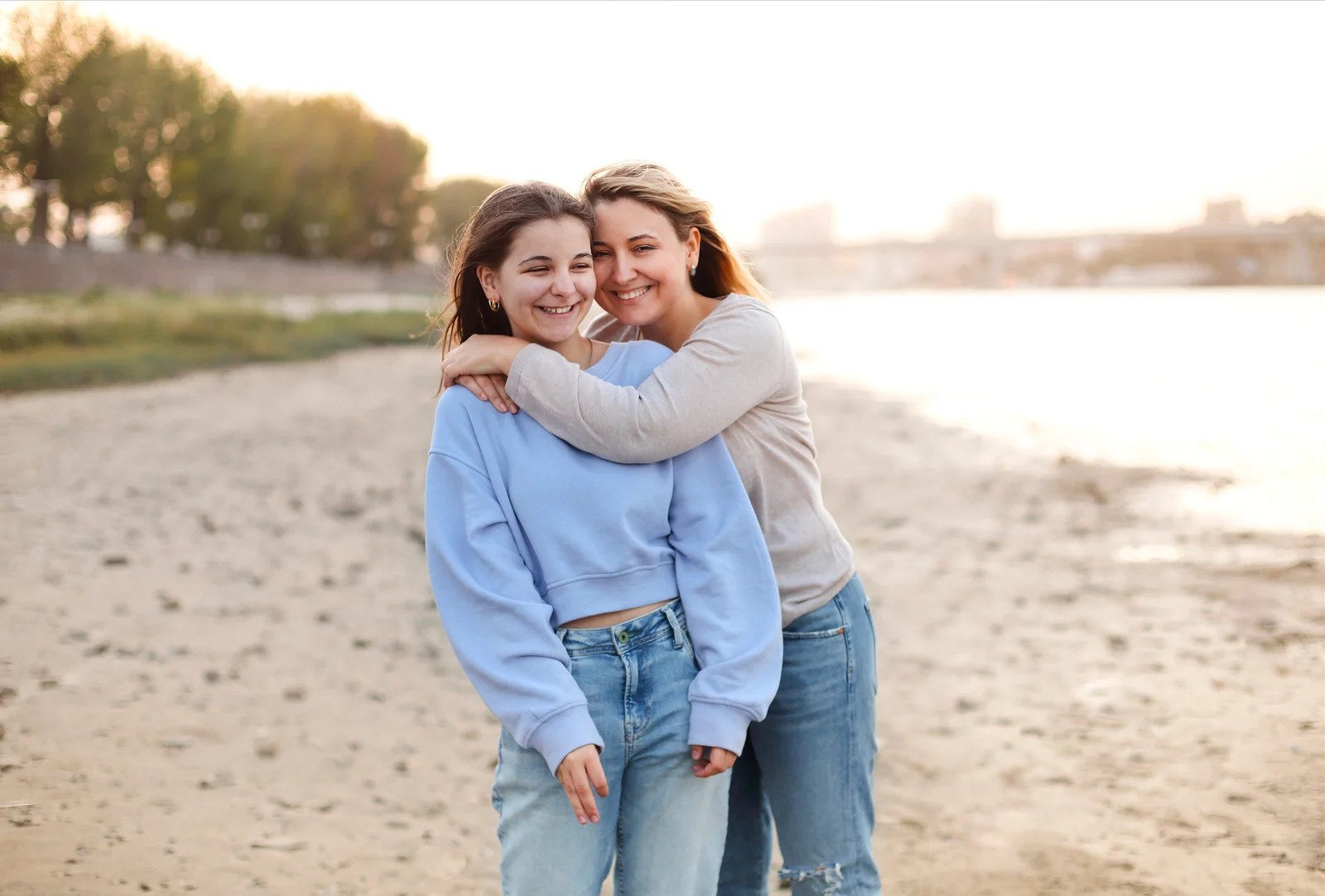 Mom and teen daughter laughing on the beach