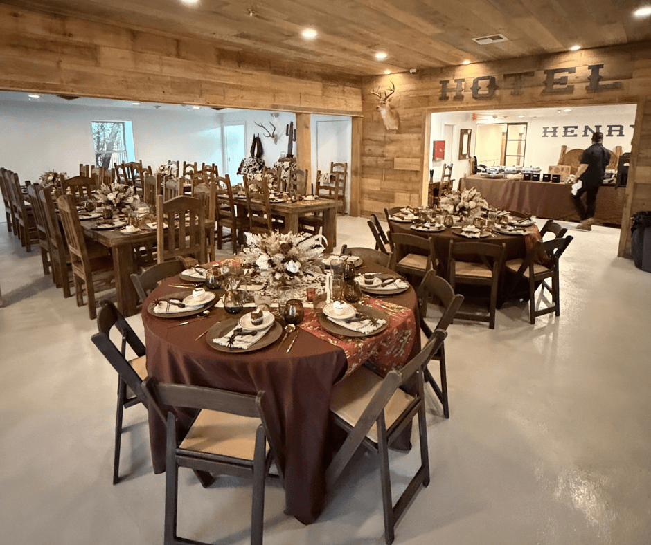 A western wedding event space at Hawkins Hope Ranch featuring wooden tables, amber glassware, and pampas grass centerpieces in a rustic hall.