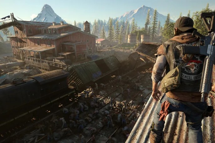 a screenshot from the video game Days Gone. The character, Deacon, stares down from a rooftop into a horde of freakish humans and a derailed train, with an old sawmill and distant mountains in the background.