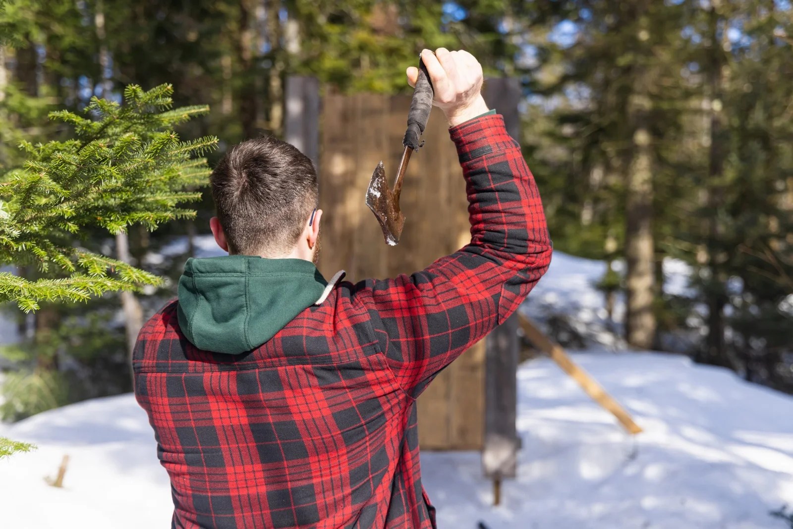 Lumberjack throwing axe at target in winter forest