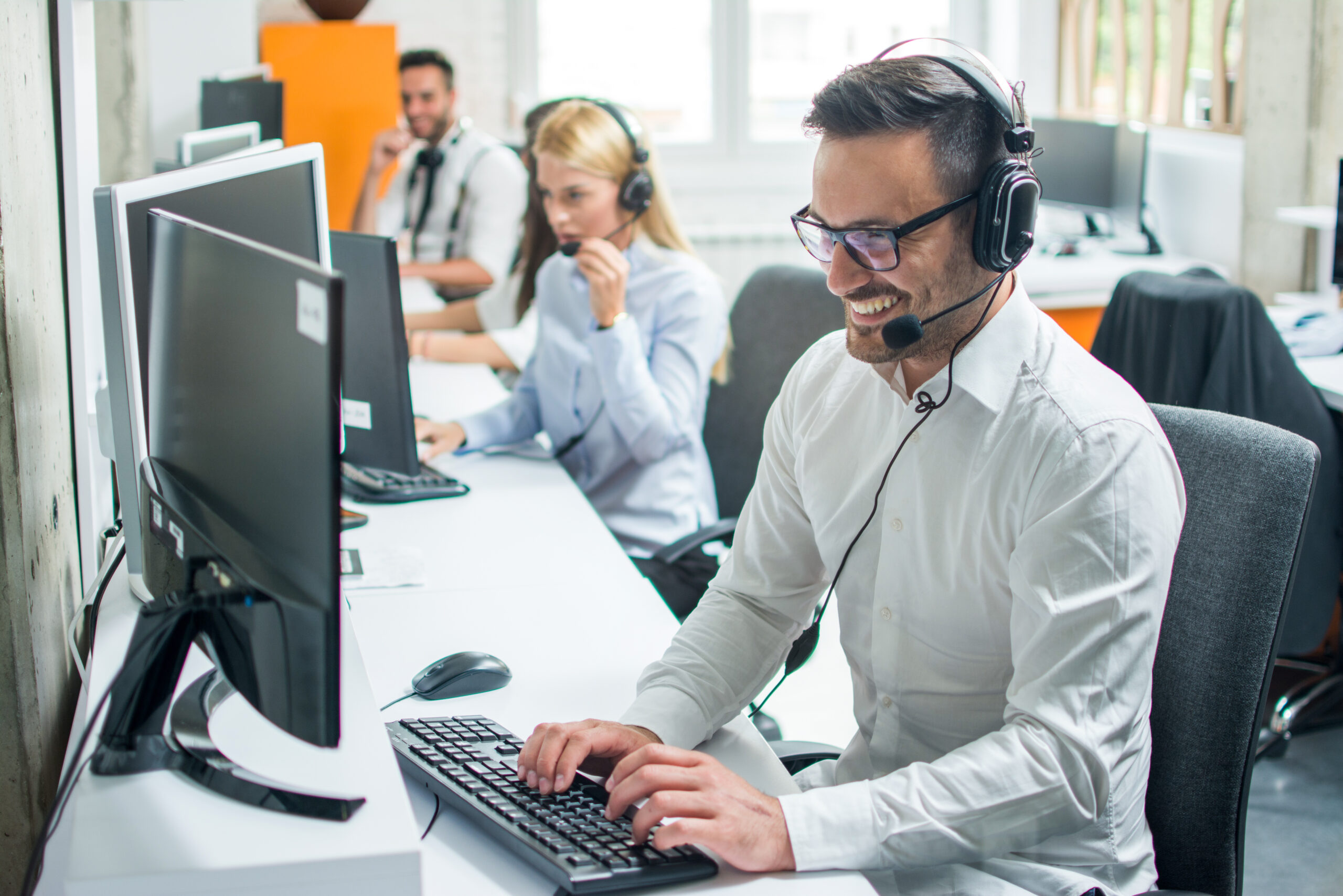 Young male technical support dispatcher with headset talking wit