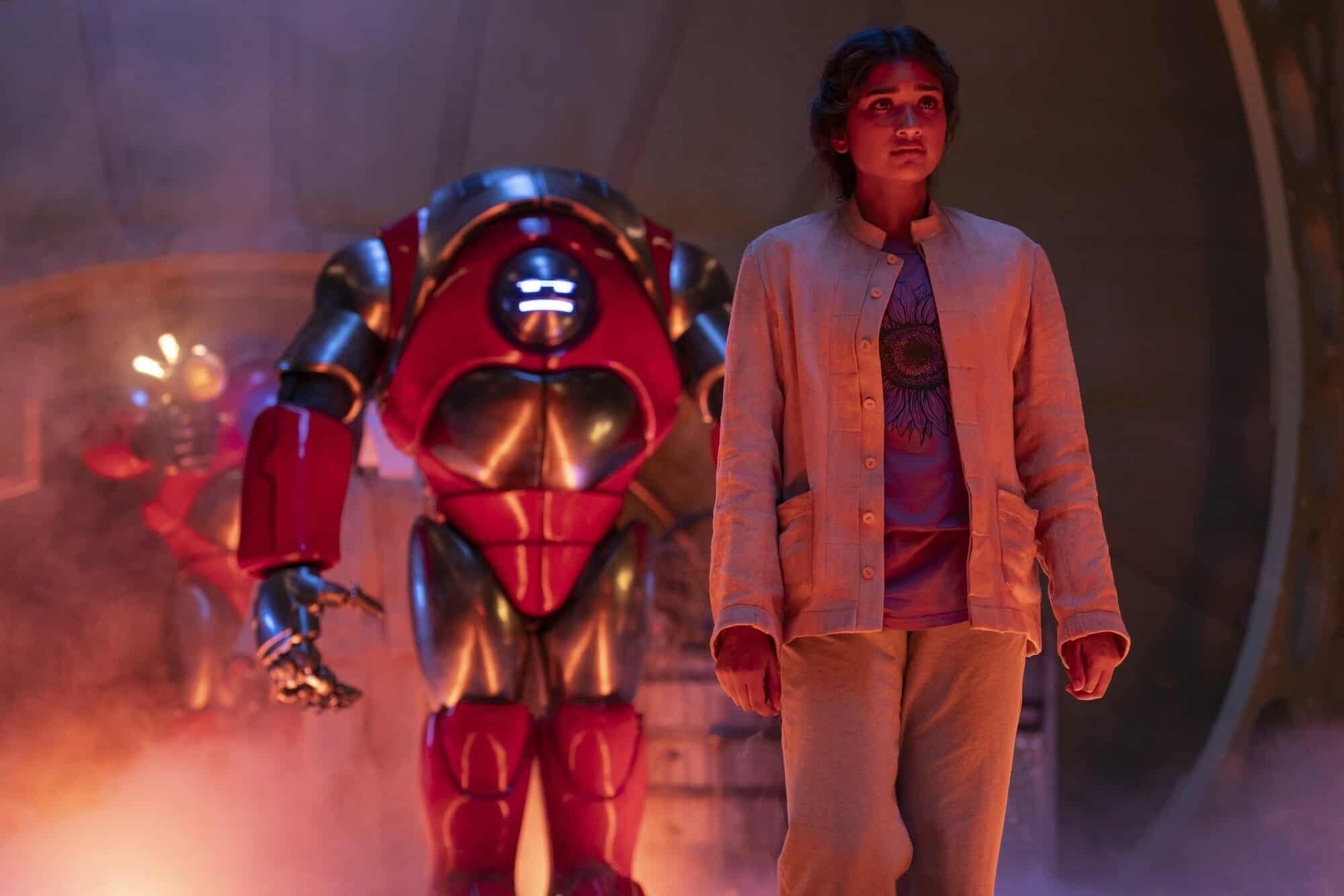 Varada Sethu as Belinda Chandra followed by a giant red robot in the Doctor Who Series 15 opener The Robot Revolution.