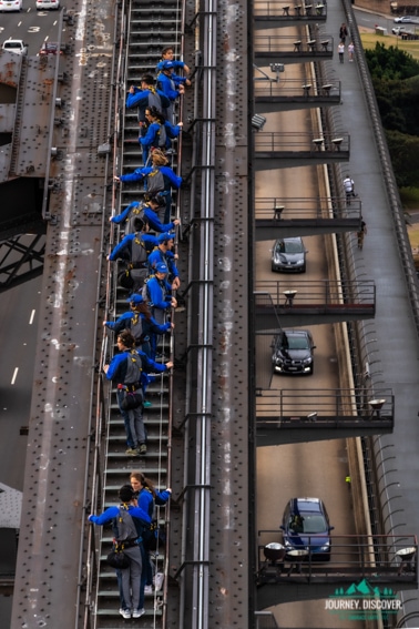 Watching the BridgeClimbers scale Sydney Harbour Bridge whilst the cars fly past.