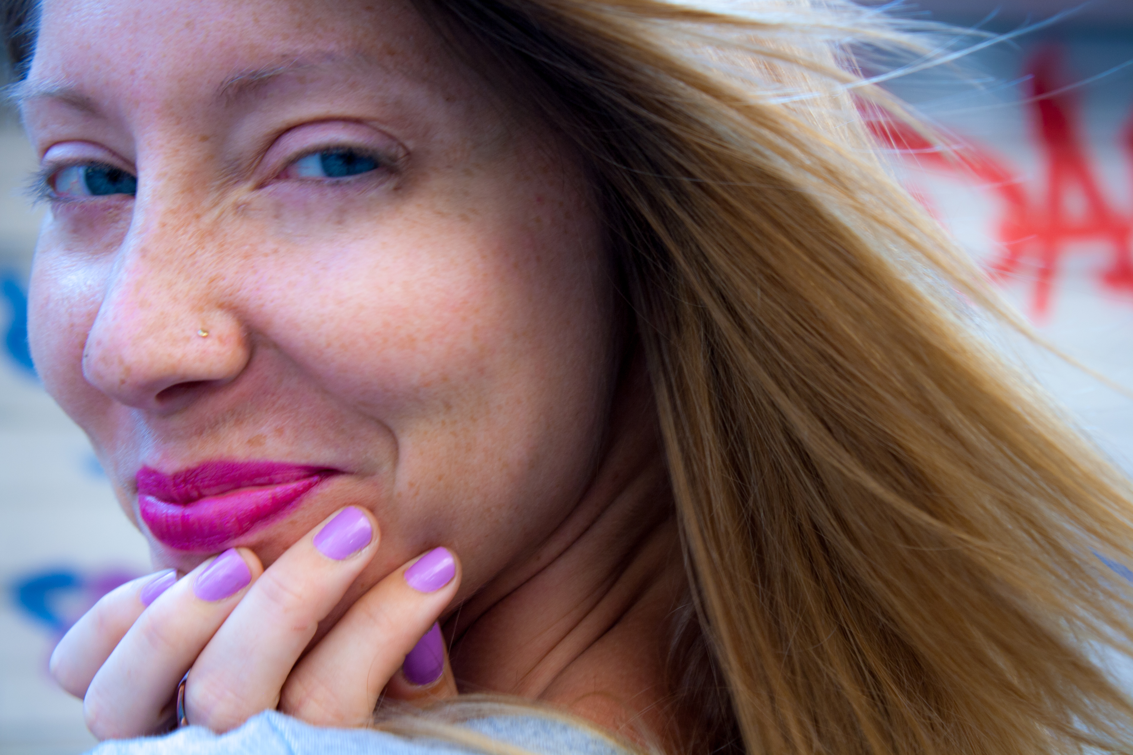 Closeup of client smiling and showing purple nail polish.