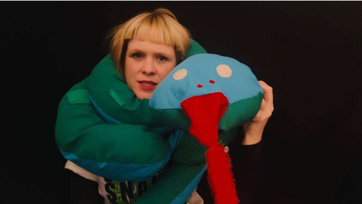 Photograph of Eilis Frawley with a large stuffed toy snake wrapped around her neck and body