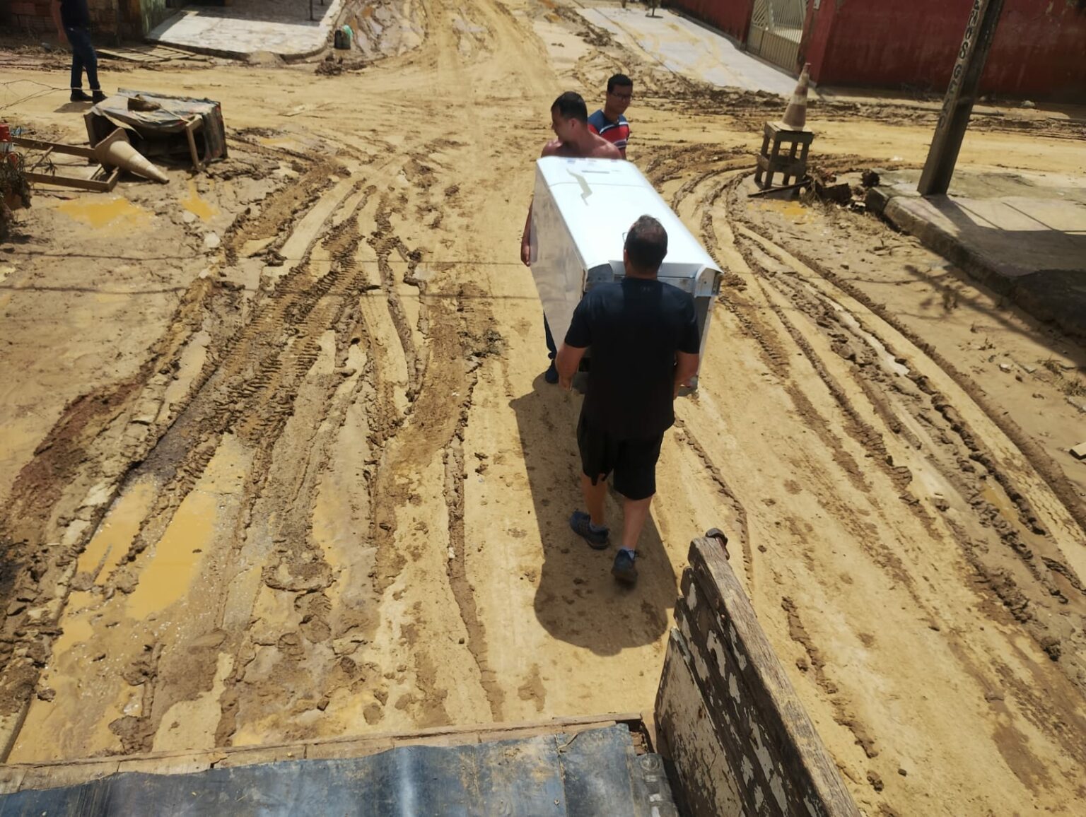 Servidores carregam móveis e eletrodomésticos em meio à lama. foto: cedida