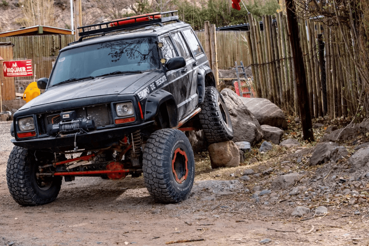 Jeep Cherokee navigating rocky terrain in a rural setting, showcasing off-road capabilities.
