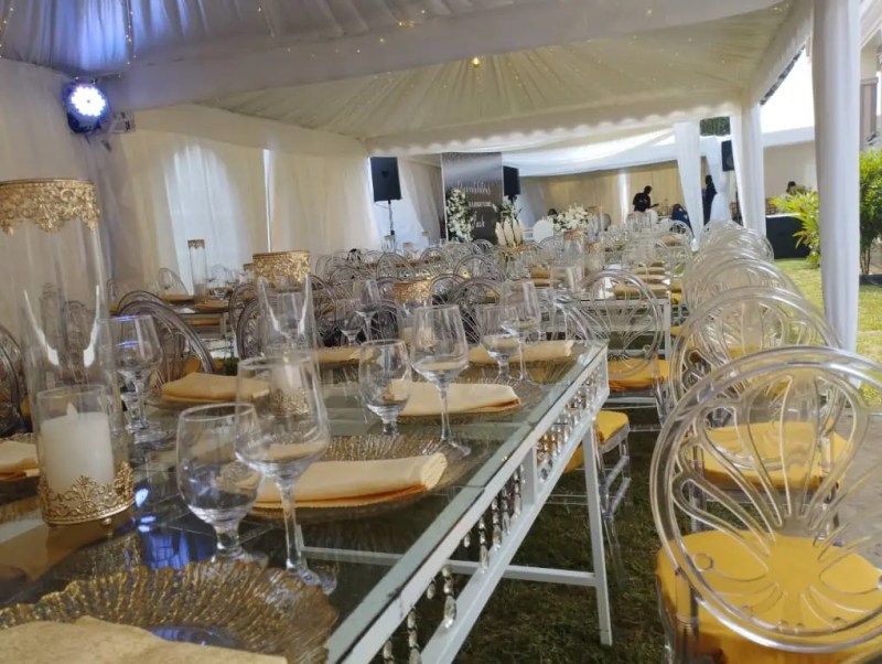 Elegant table setting under a marquee tent with glassware and gold accents