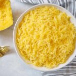 Spaghetti squash in a white bowl with two gold forks