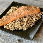 salmon over rice on a black plate