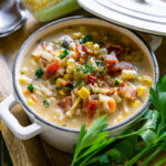 corn chowder in a white bowl with parsley.