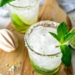 two mint mojitos on a wood serving tray