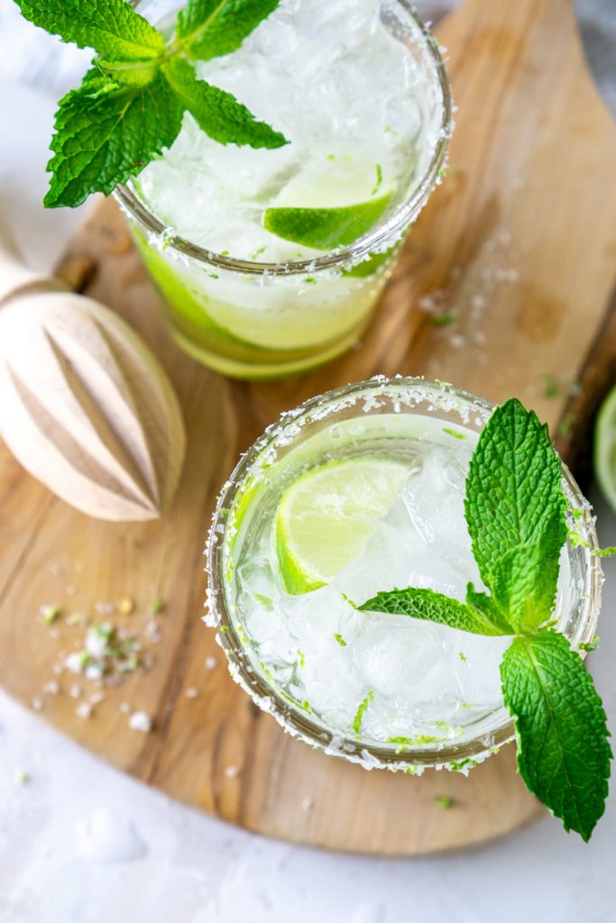 two mojitos with fresh mint and a wooden juicer