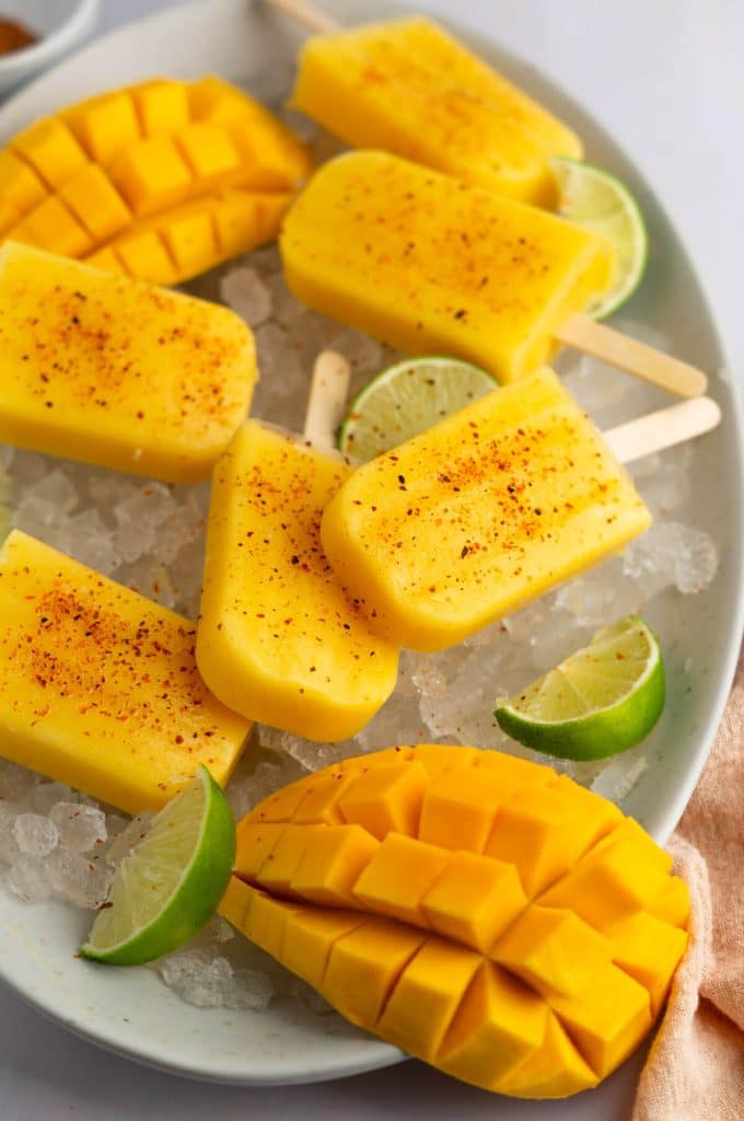 Overhead view of mango popsicles with lime slices on ice