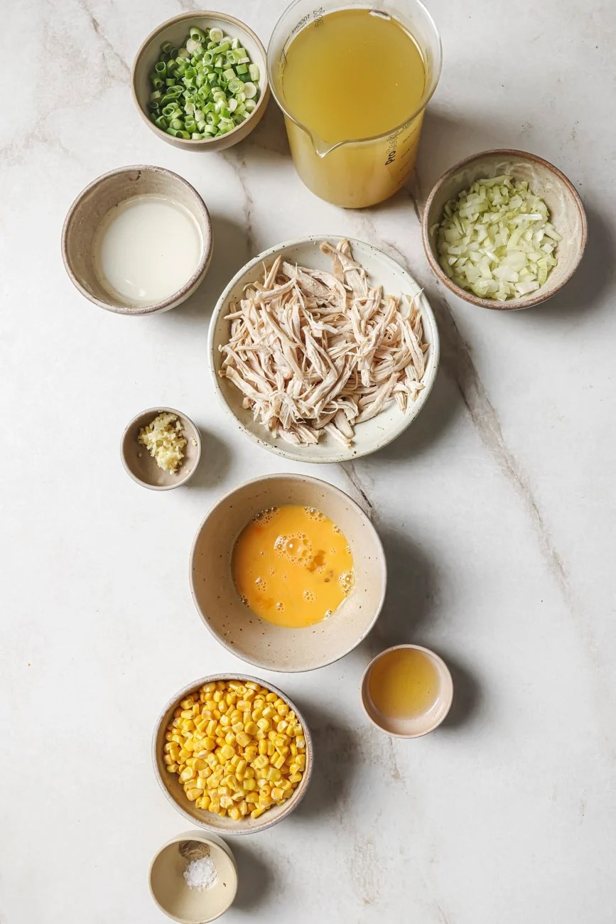 shredded chicken, corn, egg, chicken broth, and green onion in small ingredient bowls
