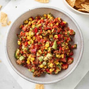 Easy avocado corn salsa with fresh tomatoes, corn, cilantro, and red onion served in a white bowl.