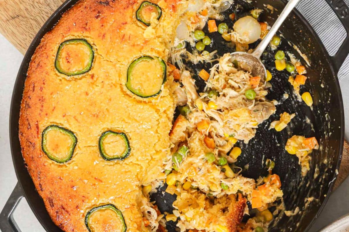 A half eaten Cornbread chicken pot pie in a pie dish.