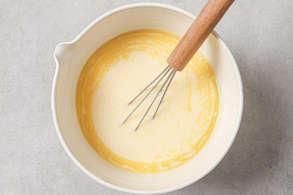 Whisking together the wet ingredients for the cornbread topping in a mixing bowl.