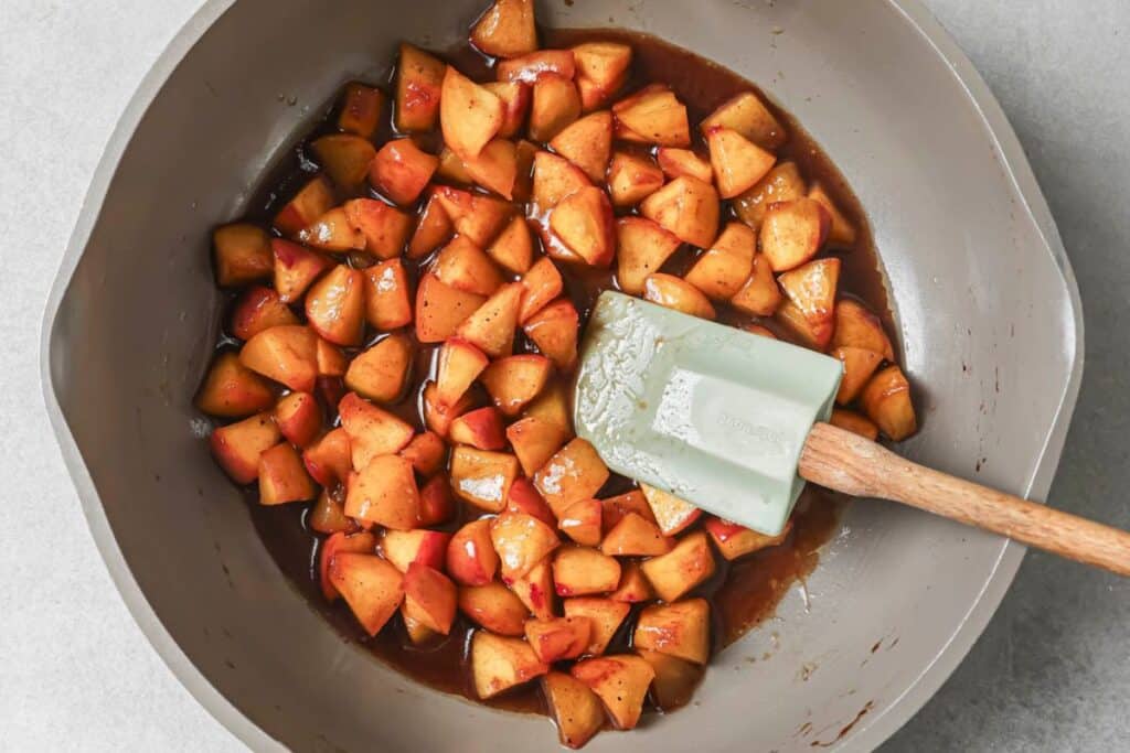 A skillet filled with diced peaches, butter, and brown sugar. 
