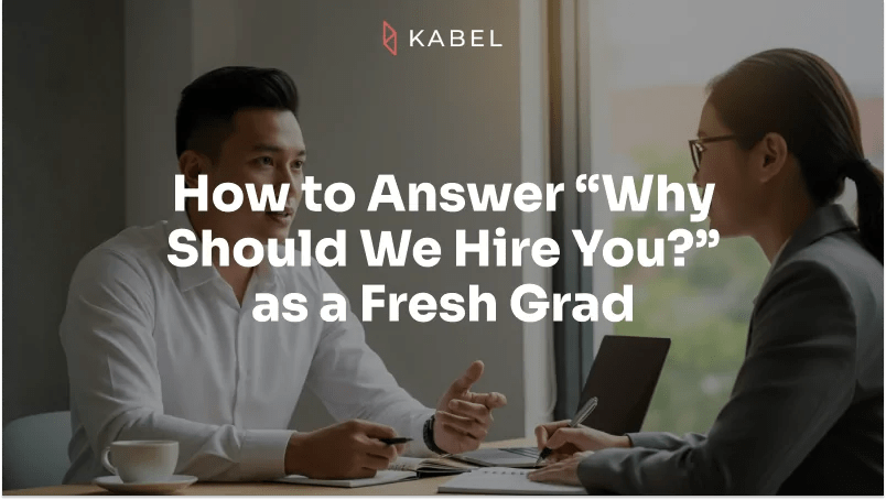 Two people in business attire have a discussion at a table with documents and coffee cups. Text overlay reads: “How to Answer ‘Why Should We Hire You?’ as a Fresh Grad.”. Kabel Job Platform
