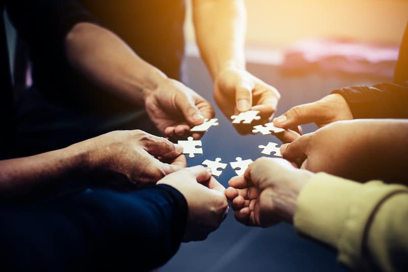 hands holding puzzle pieces in a circle
