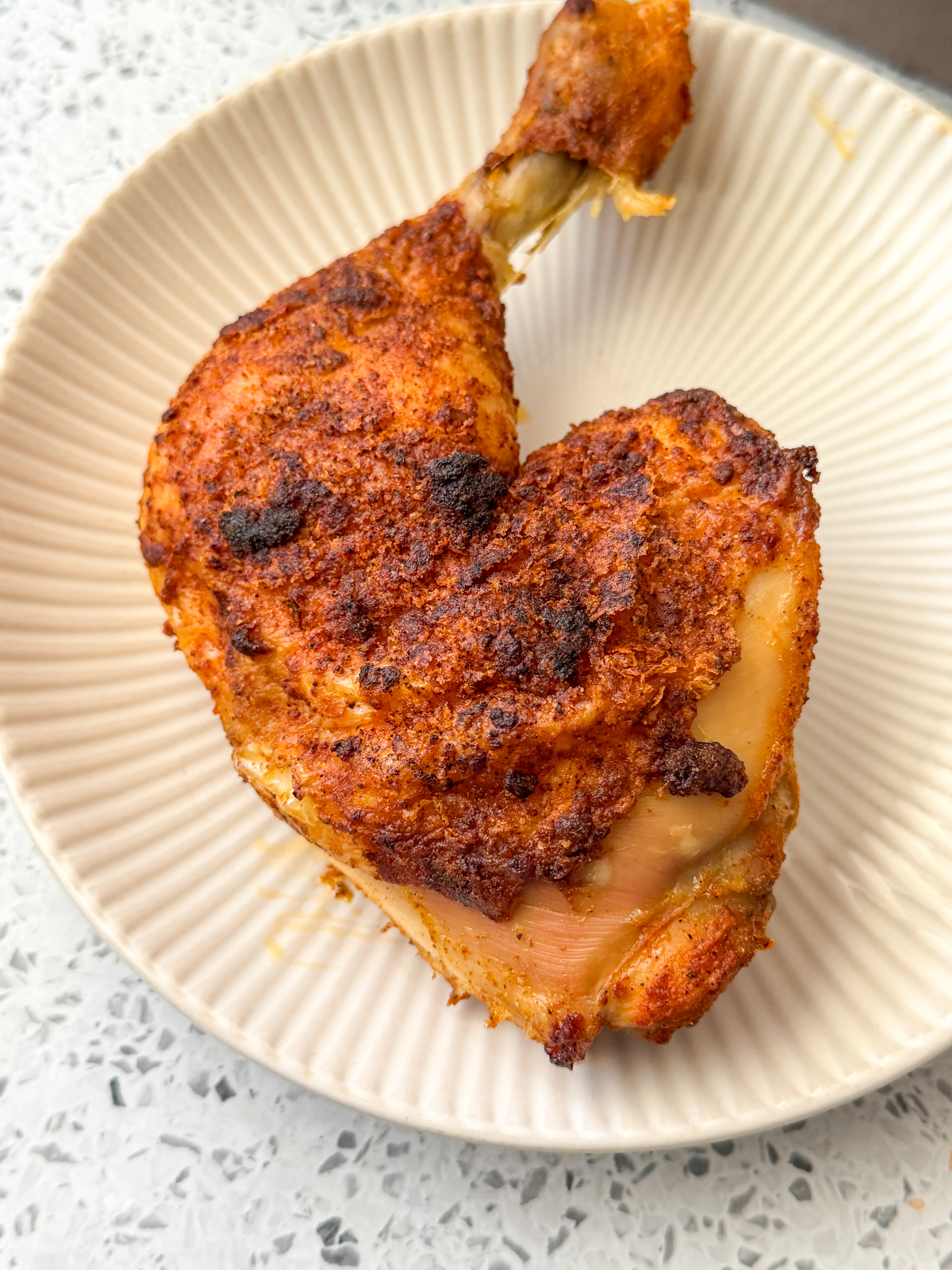 Crispy baked chicken quarter leg with golden-brown seasoned skin served on a plate