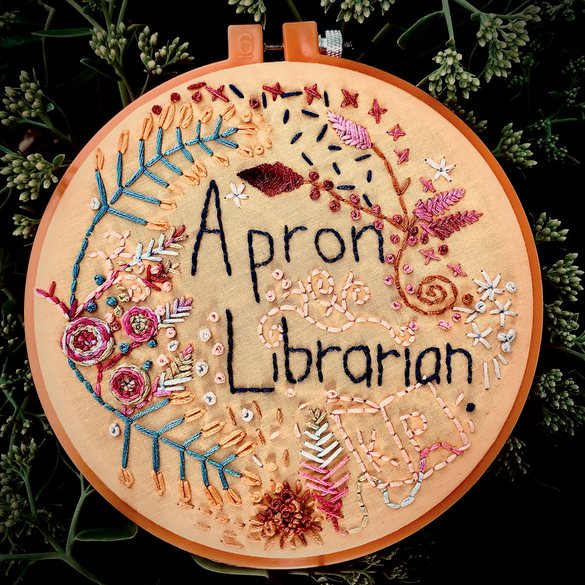 “Book It” The roses on the left were created using the woven wheel stitch in multicolored embroidery floss.