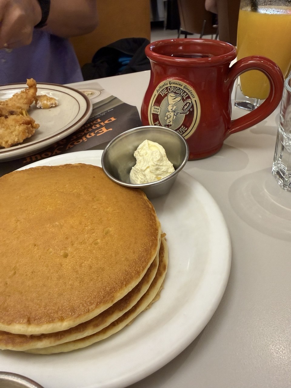 Table with pancake stack, coffee mug, and orange juice