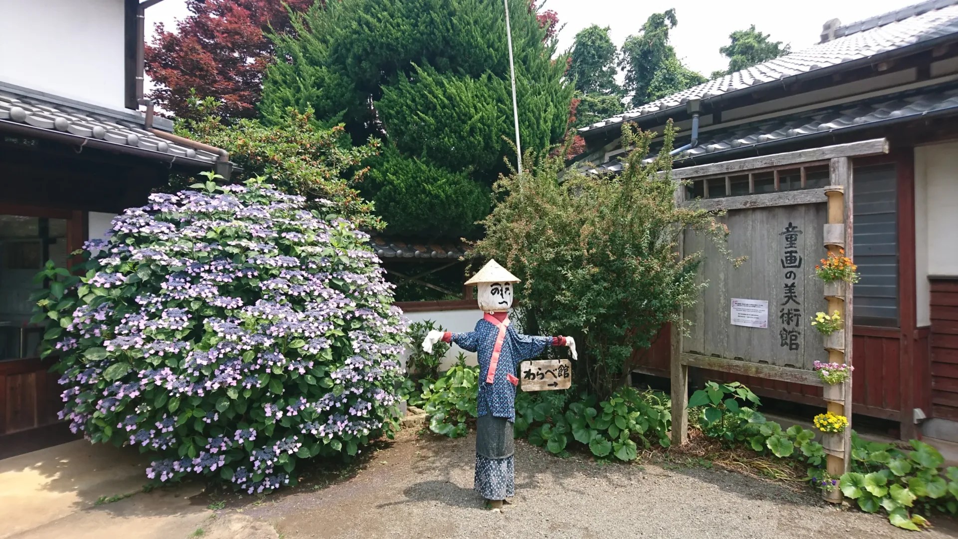 A scarecrow with a sign pointing to the entrance of the museum