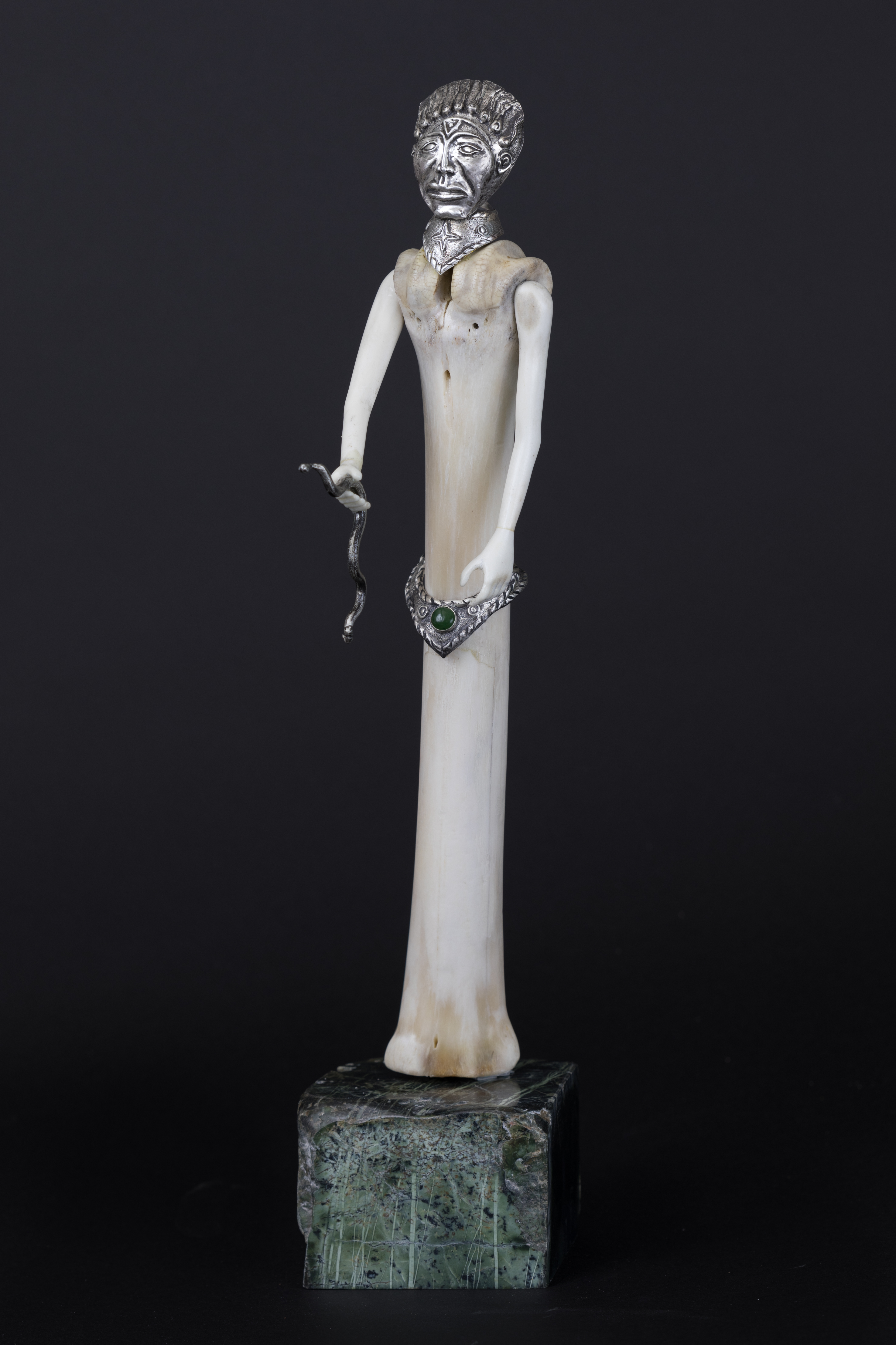 Silver repousse face and belt with jade on elk bone, with silver snake, deer antler carved arms and hands, standing on serpentine rock.